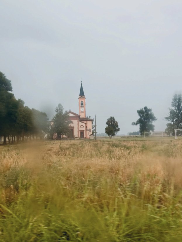 Pink church beyond a field of tall grass