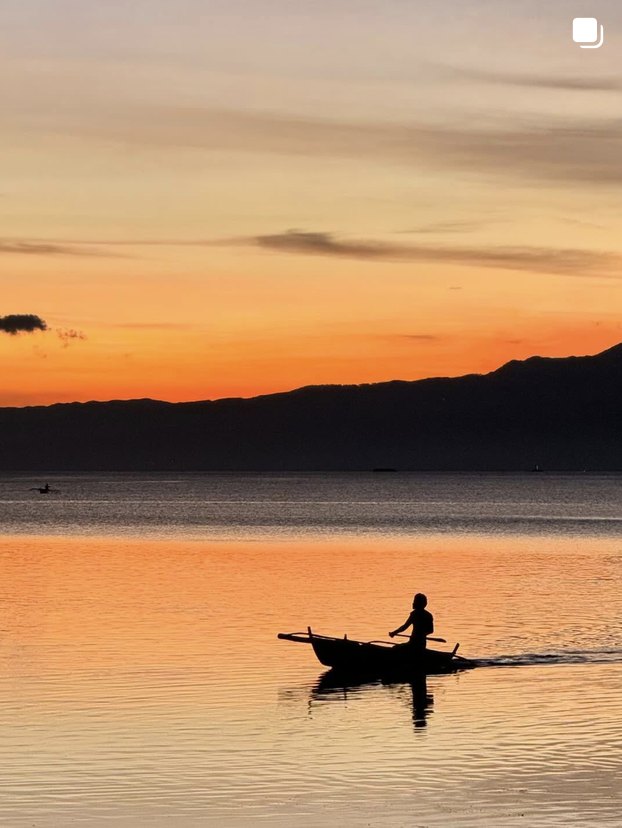 Boat silhouetted on an orange sunset sea